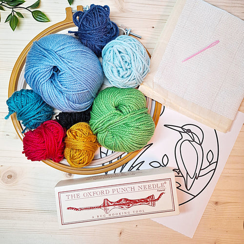 contenuto del kit punch needle "Martin Pescatore" si vedono i gomitoli di lana, i telai, l'ago Oxford, il disegno e la tela