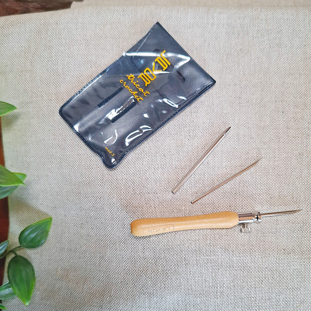 punch needle Lavor con le 3 punte da 2 mm, 2,5 mm e 3 mm disposte sopra il tessuto di misto lino per far capire che sono gli aghi adatti a questo tessuto