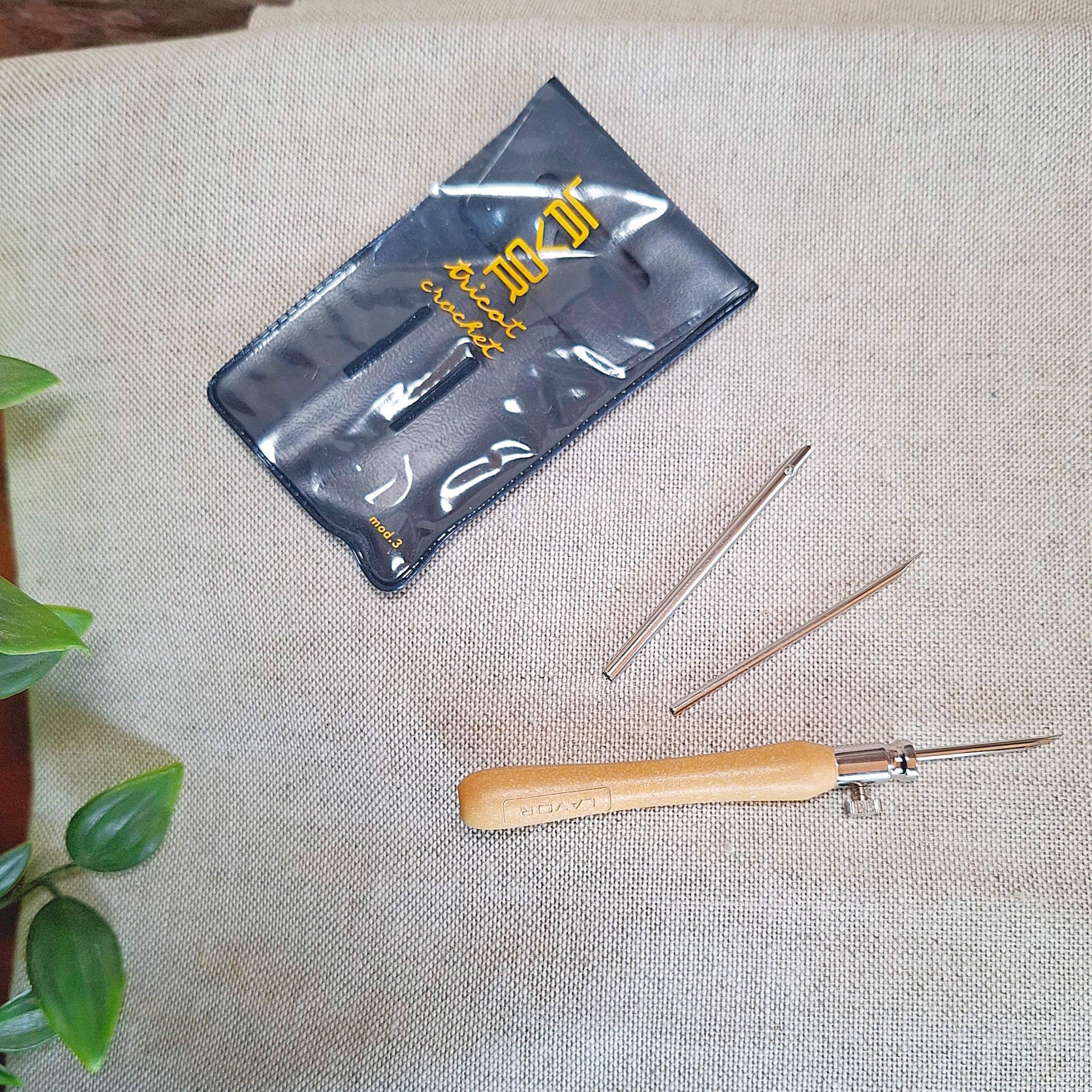 punch needle Lavor con le 3 punte da 2 mm, 2,5 mm e 3 mm disposte sopra il tessuto di misto lino per far capire che sono gli aghi adatti a questo tessuto