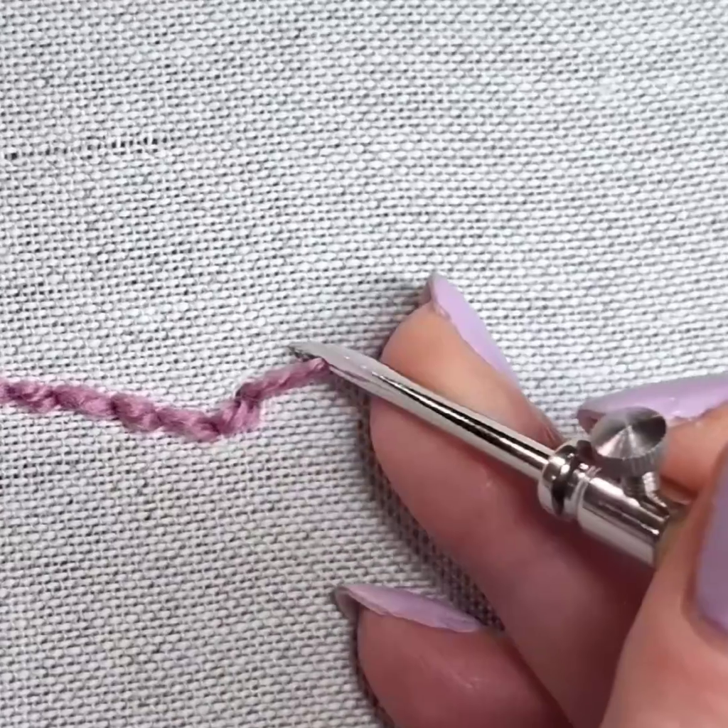 misto lino per punch needle fine, si vede un ago fine che fa dei punti su questo tessuto