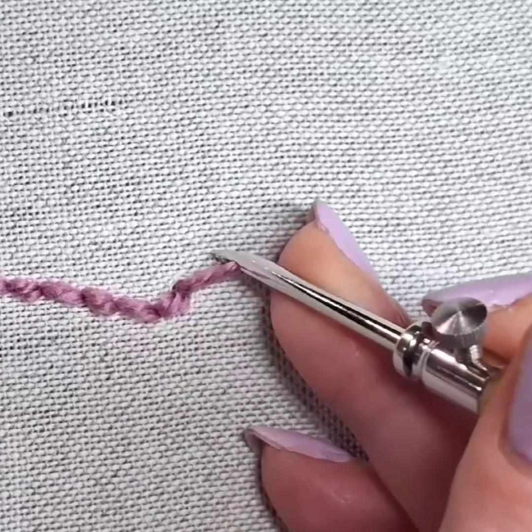 misto lino per punch needle fine, si vede un ago fine che fa dei punti su questo tessuto